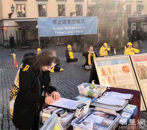'图5:俄罗斯裔的钢琴家维罗妮卡用行动支持法轮功学员,她签完了字后邀请学员当天晚上和她一起去参加一个全世界受独裁者迫害的研讨会,帮助传播真相。'