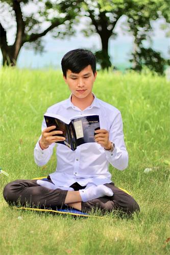 '图2:阮友维听完李洪志老师九讲讲法后,解开他心中许多疑惑。图为阮友维阅读越南版《转法轮》。'