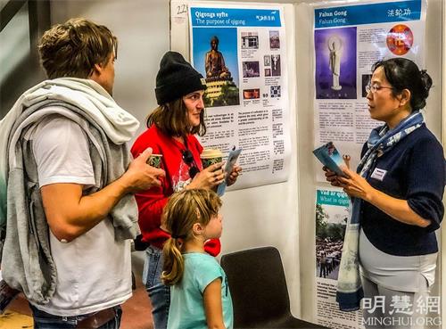 '图2~3:法轮功学员的展台前参观者们络绎不绝,学员向与会者介绍以修炼真、善、忍为原则的法轮功。'