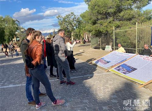 '图4~5:二零二一年十二月十二日,法轮功学员在雅典卫城山下演示功法,行人驻足观看,拍照留念。'