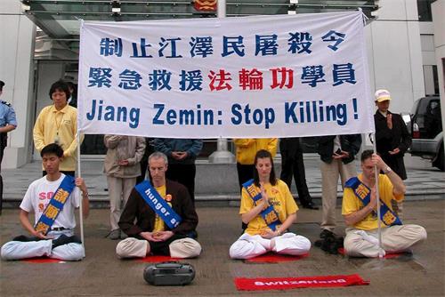 '图2:二零零二年三月十四日,四名瑞士和十二名香港的法轮功学员在西区中联办前绝食静坐,抗议中共迫害残杀大陆法轮功学员,遭警方武力粗暴抬走。'