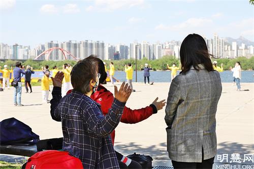 图20:首尔市民们在观看汝矣岛汉江公园法轮功学员集体炼功,并跟随学习