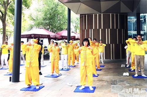 '图8:法轮功学员在市中心向居民展示法轮大法五套功法'
