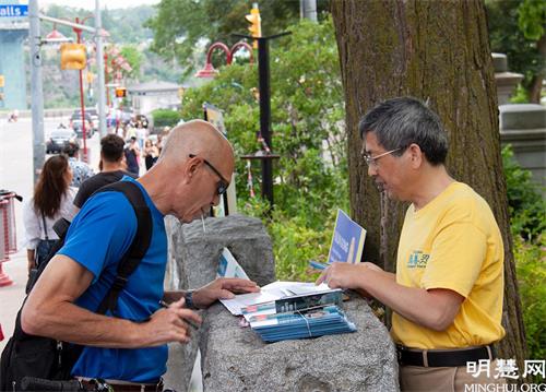 '图3:游客在尼亚加拉大瀑布炼功点了解法轮功真相并签名支持反迫害。'