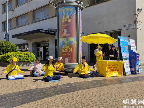 图2:法轮功学员在普利茅斯(Plymouth)市中心设立真相点。图为法轮功学员正在演示功法。