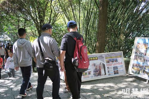 图3-4:青龙步道上,大陆游客停下脚步,关注法轮功真相。