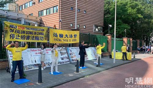 '图6~7:法轮功学员在中共大使馆前面对前来排队的华人讲真相,并集体炼功'