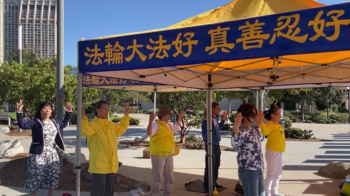 '图3:法轮功学员的功法展示吸引众多游客驻足'