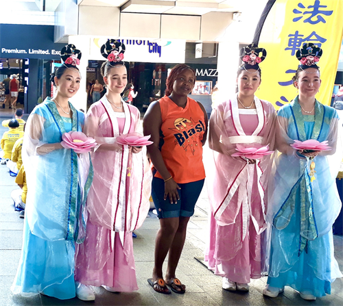 图2:由青年法轮功学员组成的仙女队中的爱莲(Ai Lian,左一)与阿什利(Ashleigh,左二)应邀与路人合影