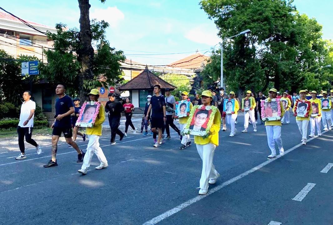 '图4:行进间,峇里岛学员手持被中共迫害致死的中国法轮功学员的照片。'
