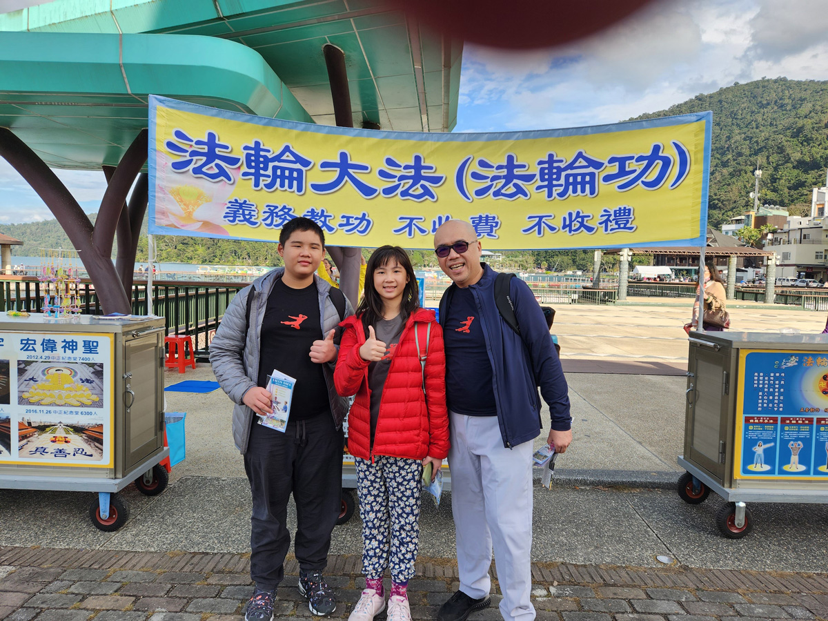图7:来自印尼的一家人,手持莲花和资料在展板前拍照