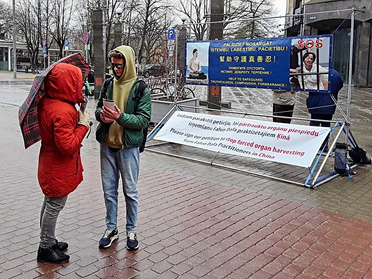 '图1~4:二零二三年四月一日,脱维亚法轮功学员在首都里加市举办讲真相活动。许多路人驻足与学员交谈,了解真相。'