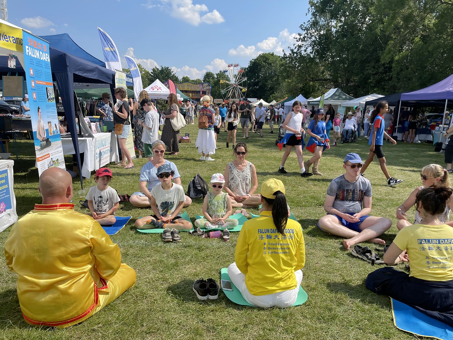图1~2:二零二三年六月十日星期六,英国乡村日,英国法轮功学员在法轮功展位前,教民众学炼功法,大人和孩子们都喜欢学法轮功。