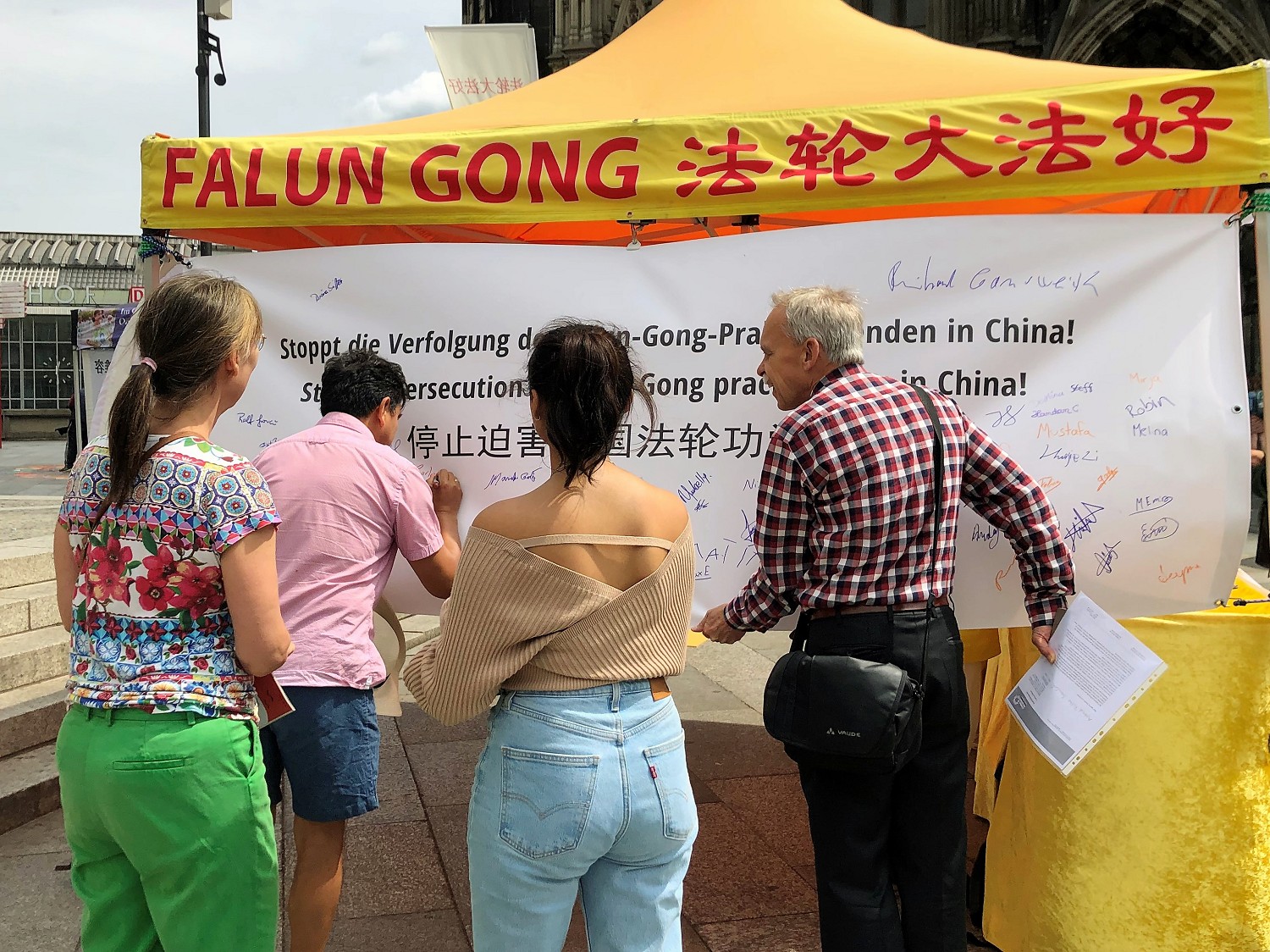 图4:民众在写有“停止迫害中国法轮功学员!”的大型横幅上签名,支持制止迫害。
