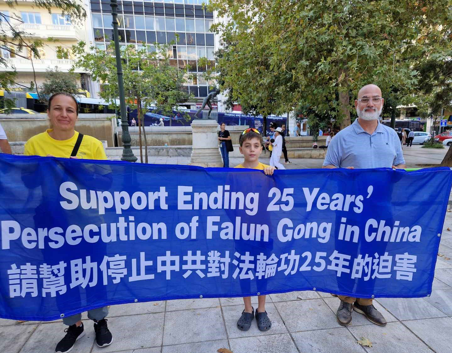 图13:朱莉亚一家举着横幅:“支持制止在中国对法轮功二十五年的迫害”。
