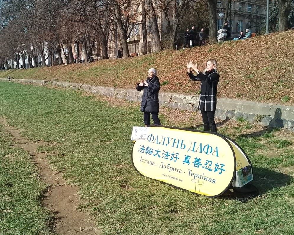 '图5:在乌日哥罗德市中心堤岸边,学员们向市民演示功法传递法轮大法的美好。'