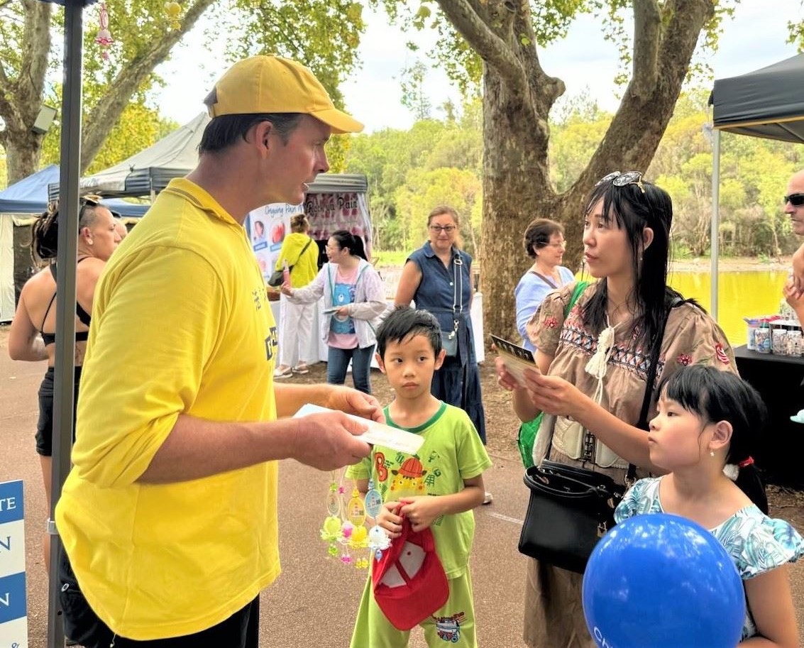 '图2:法轮功学员在展位上向人们介绍法轮功真相。'