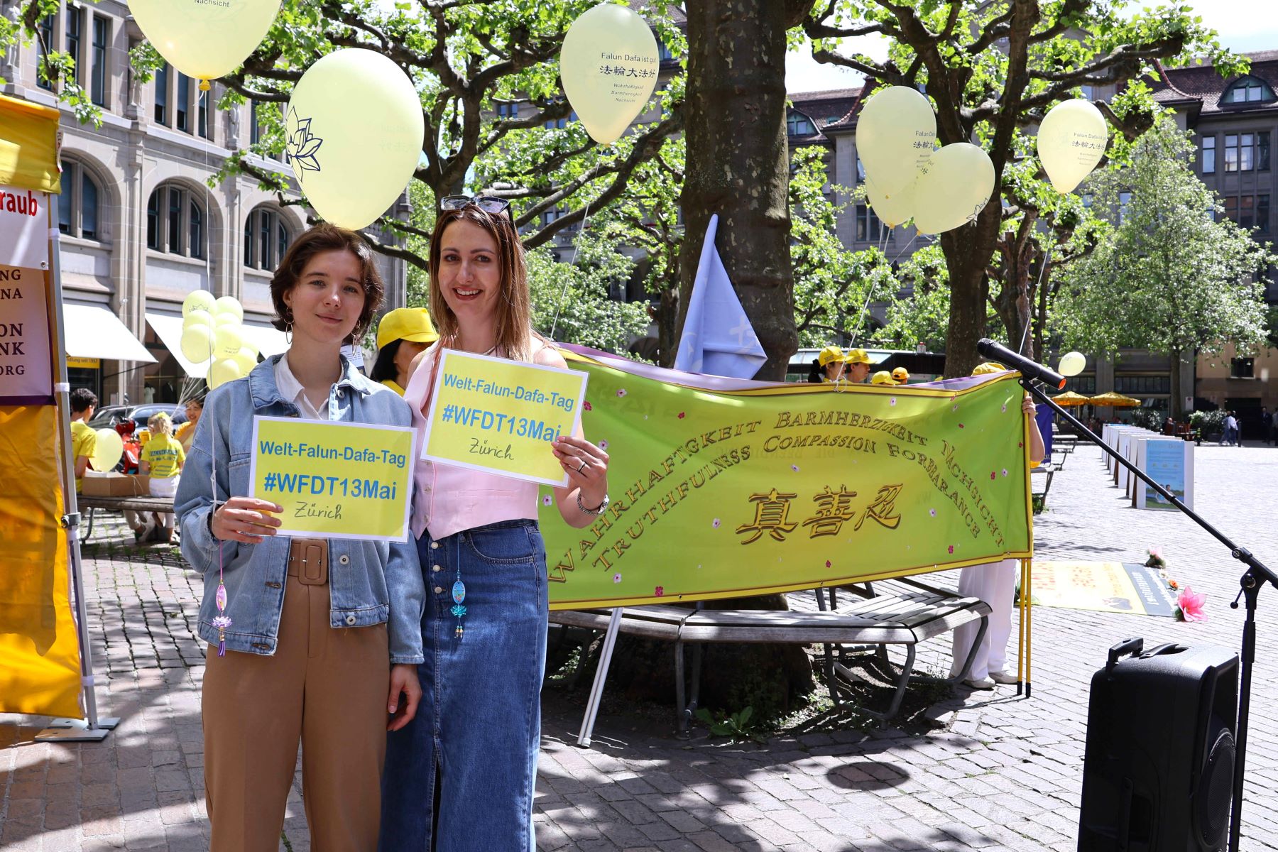 图12:芙拉达‧卡普伦和达莉娅‧韦奇举牌与法轮功学员同庆法轮大法日。