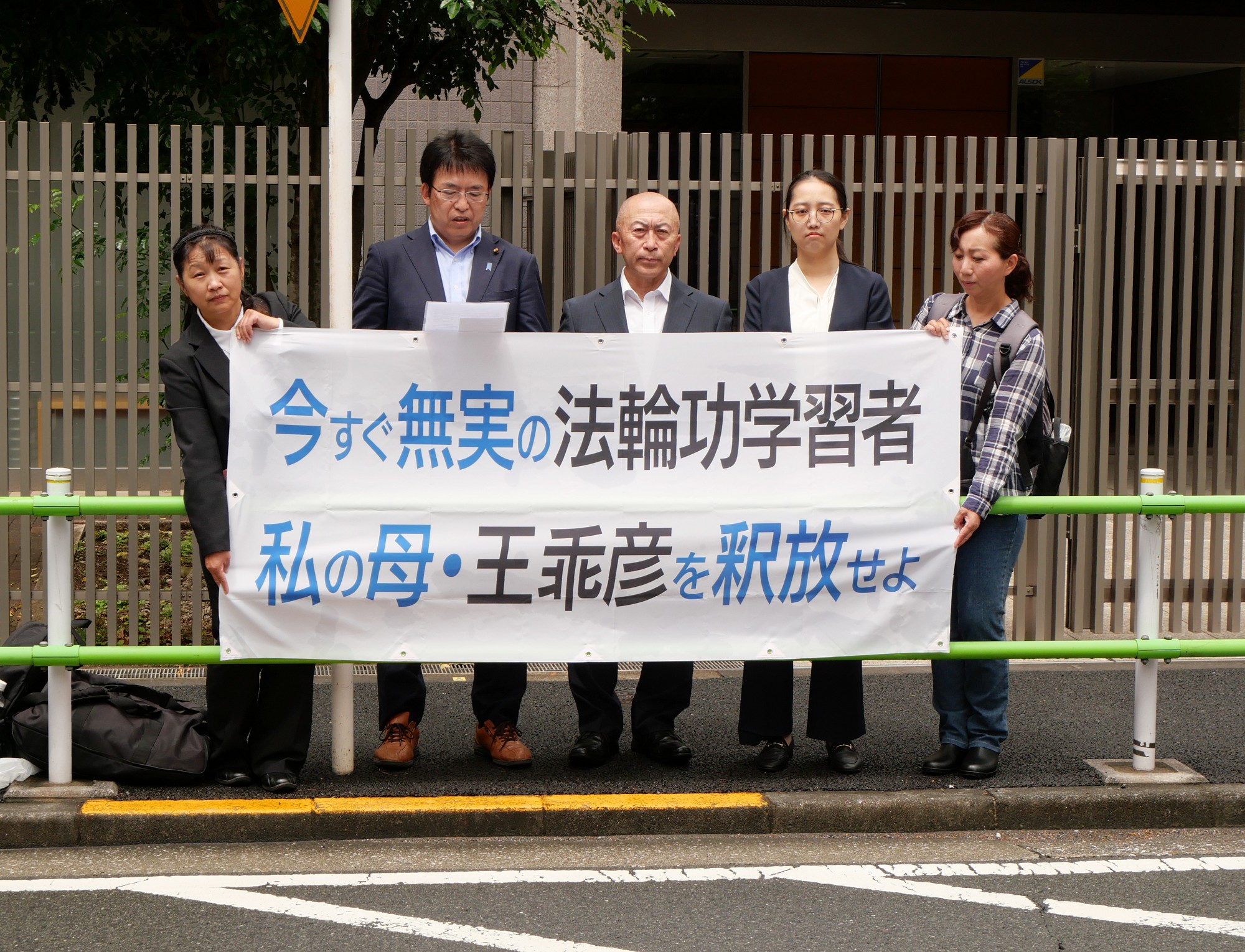 图1:二零二四年五月二十八日,日本法轮功学员和议员来到东京六本木的中国大使馆前,呼吁立即释放今年四月被中共绑架的法轮功学员王乖彦。正在宣读“忠告书”的丸山治章先生(左二)