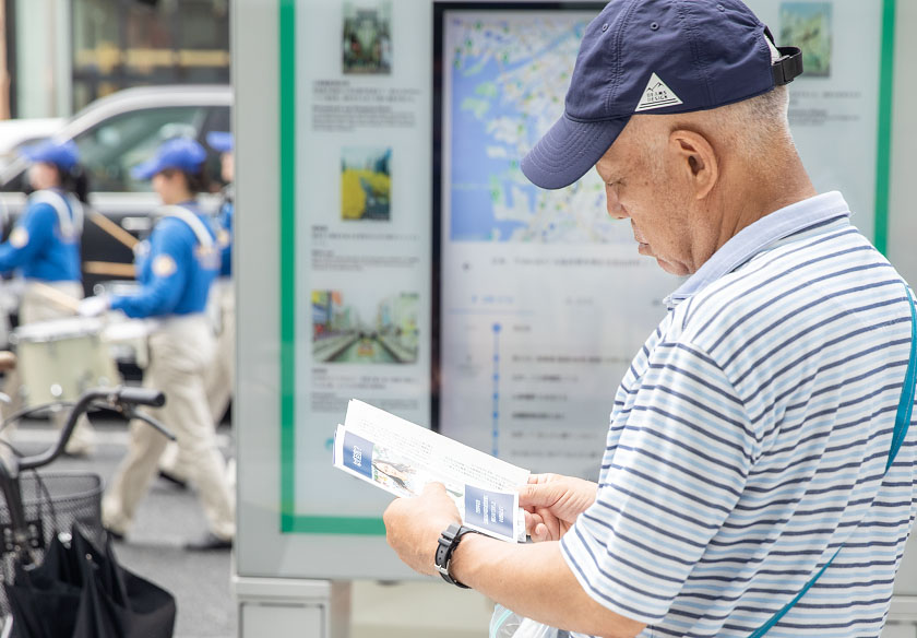 图18:二零二四年七月十四日下午,日本法轮功学员在大阪举办七•二零反迫害游行活动,日本市民接过法轮功简介资料,马上阅读起来。