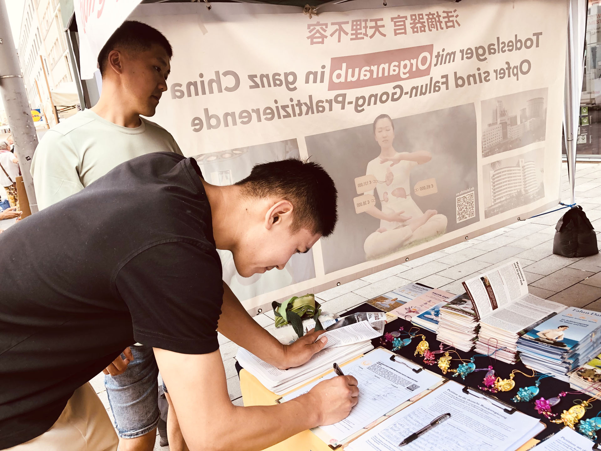 图13: 尼泊尔年轻人阿克尔别克(Akylbek)(左)和史坦斯特(Stansted)签名声援法轮功学员反迫害的活动