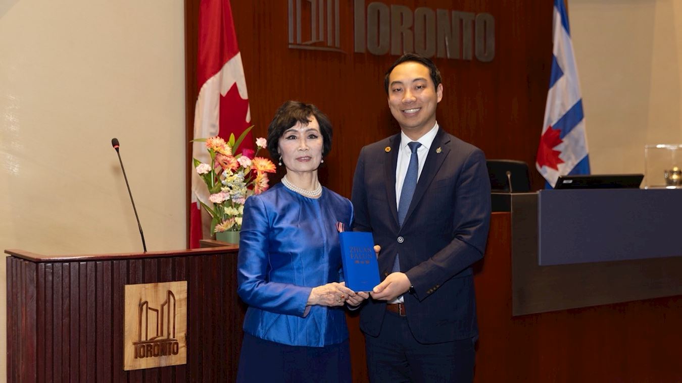 '图3:张铁钧(Tia Zhang)女士赠送法轮功著作英文《转法轮》给加拿大国会议员王启荣(Kevin Vuong)'
