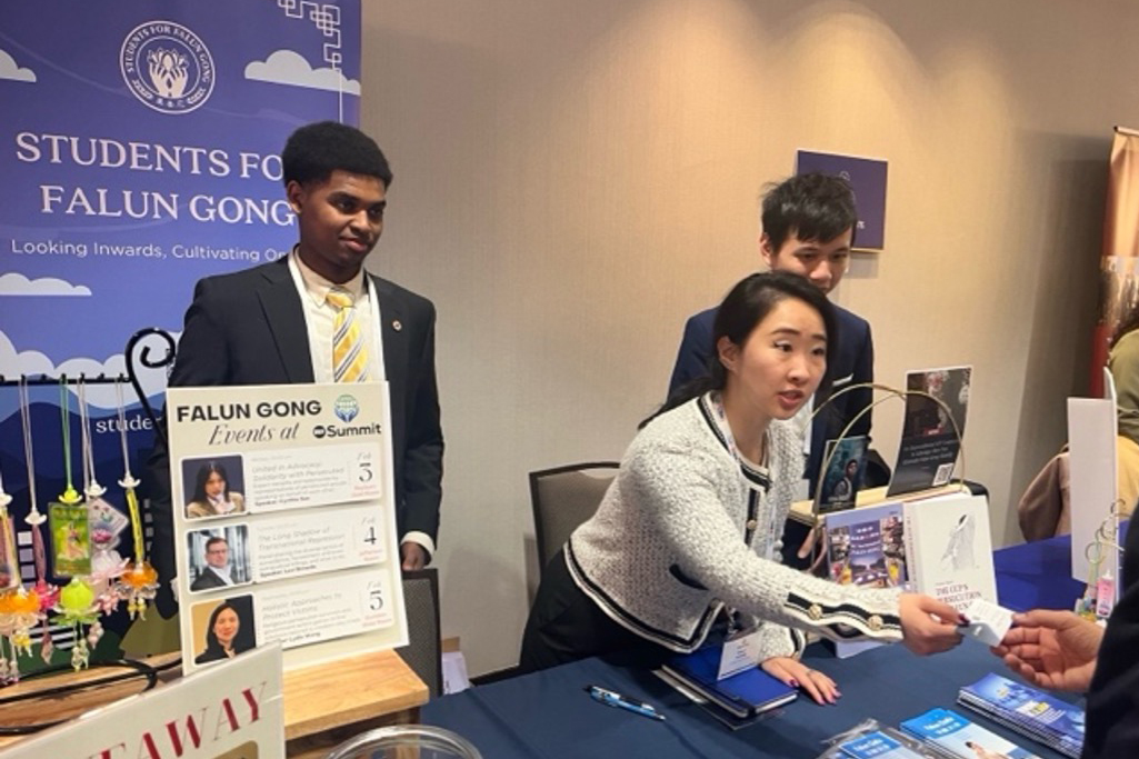 图4:年轻的法轮大法学员在展位上向与会者介绍法轮功及其所面临的迫害。