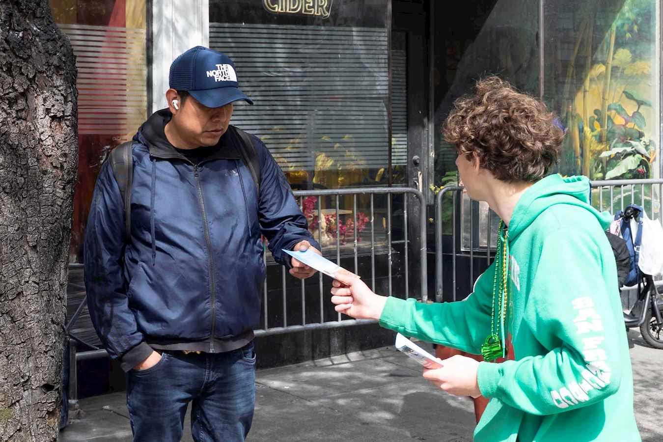 '图12:旧金山高中生雅各布·哈格一路上跟着法轮功学员的队伍,高兴地向人们派发法轮功真相资料。'