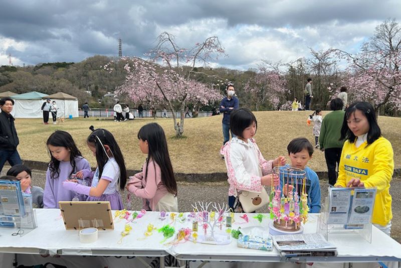 '图7~9:在丰田市水源公园樱花节期间吸引不少天真可爱的小孩儿,领着大人前来拿取法轮功真相资料与写有“法轮大法好、真善忍好”小莲花。'